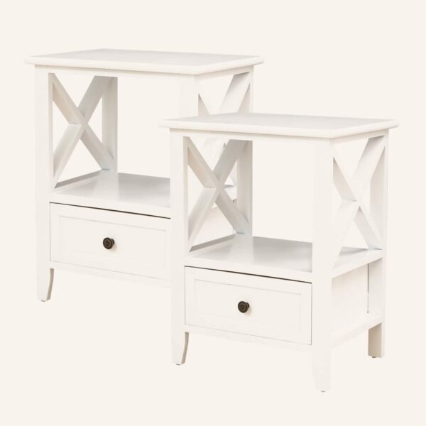 Two white rustic bedside tables with storage drawers and X-frame sides.