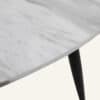 Close-up of a minimalist marble effect round coffee table with black tapered leg.
