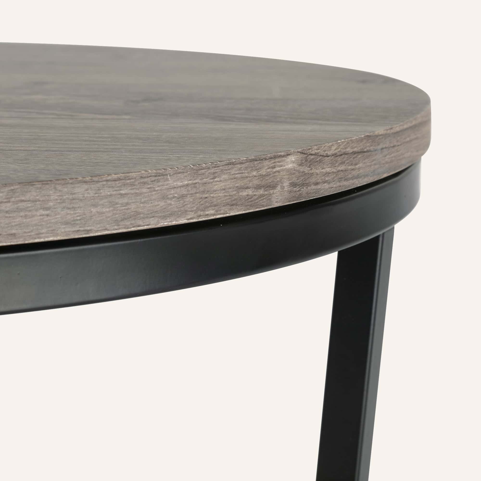 Close-up of a modern nesting coffee table with wooden top and black metal legs.